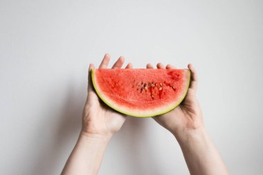 Eller beyaz arka planda sulu karpuz dilimini tutuyor..