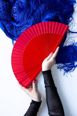 Mavi şallı kırmızı yelpaze tutan bir kadın el..