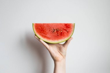 Beyaz arka planda bir dilim taze karpuz tutuyor..