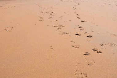 Kumlu sahilde ayak izleri. Hafif dalgalar ve doğal ışık..