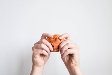 Elinde taze pişmiş kahverengi rulo tutan biri var. İki eli de beyaz arka planda..