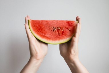 Eller beyaz arka planda taze karpuz dilimi tutuyor..