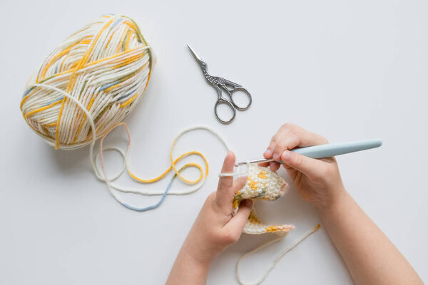 Детские вязания с красочной пряжей на белом фоне.