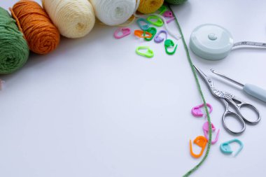 Örgü aletleri ve beyaz yüzeyde dikiş izleri olan renkli iplik topları.
