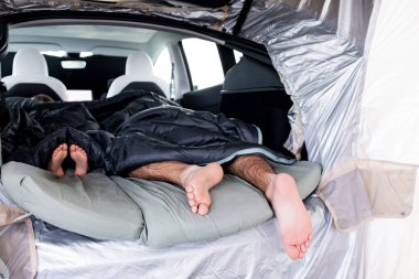 Ailesiyle kamp yapan rahat bir araba. Yetişkinler ve çocuklar uyku tulumlarıyla arabada uyuyorlar..