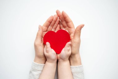 Anne ve çocuk elleri beyaz arka planda kalp sembolü taşıyor..