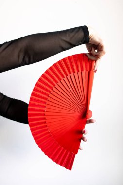 Beyaz arka planda canlı kırmızı yelpaze tutan bir kadın el..