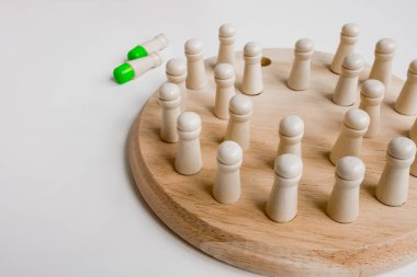 Tahta çivili solitaire oyun tahtası beyaz arkaplanda yeşil ve beyaz çiviler.