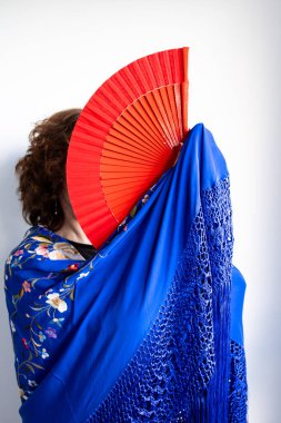 Mavi şallı, kırmızı yelpazenin arkasına gizlenmiş bir kadın..