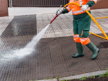 İşçi gücü şehir kaldırımını hortum ve güvenlik malzemeleriyle yıkıyor.