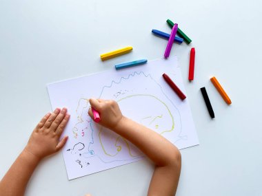 Beyaz kağıt üzerine renkli renkli renkli renkli çizimler yapan çocuk..