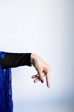 Mavi kumaşlı bir kadın el hareketi ve arka planda kırmızı tırnaklar..