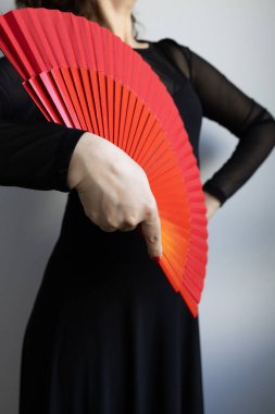 Siyah elbiseli kırmızı yelpaze tutan kadın..