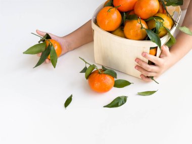 Beyaz arka planda taze portakal sepeti taşıyan çocuk.