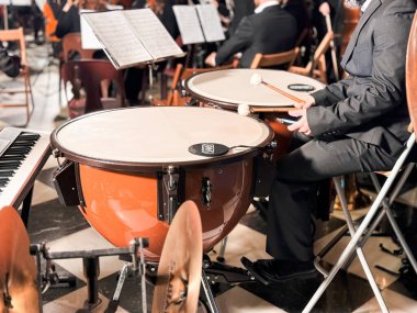 Bir orkestra konserinde timpani çalan erkek müzisyen.