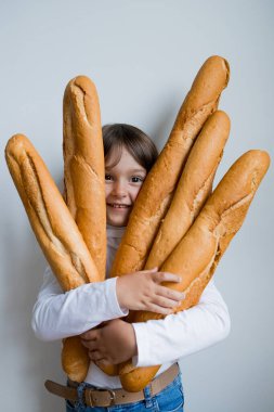 Beyaz arka planda taze baget tutan mutlu beyaz çocuk..