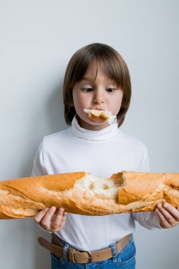Kafkas çocuk basit bir arka planda taze bir baget yiyor..