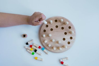 Çocuk eli beyaz masada tahta tahta tahta oyunuyla oynuyor.