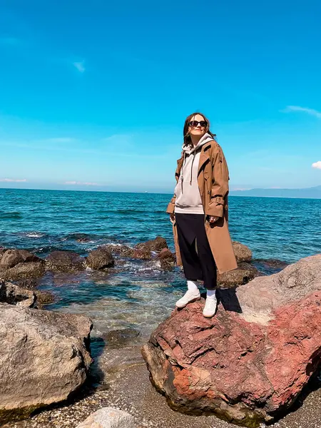 Güneşli bir günde kayalık kıyı şeridinde genç beyaz kadın..