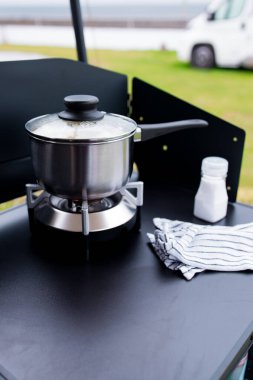 Açık hava kamp sobası, tencere ve tuzluk masanın üstünde..