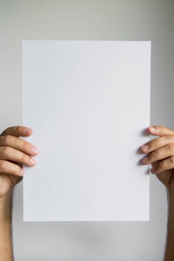 Boş kağıdı düz arkaplanda tutan eller.