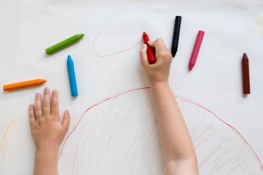 Kağıda renkli boya kalemleri çizen çocuk..
