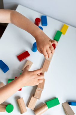 Beyaz masada renkli tahta bloklarla oynayan bir çocuk. Yüksek kalite.