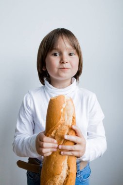 Beyaz gömlekli, arka planda beyaz ekmek tutan beyaz bir çocuk..