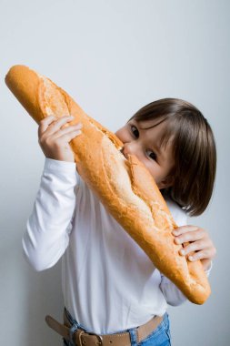 Genç beyaz çocuk büyük baget ekmeğin tadını çıkarıyor. Zevk ve merakla dolu..