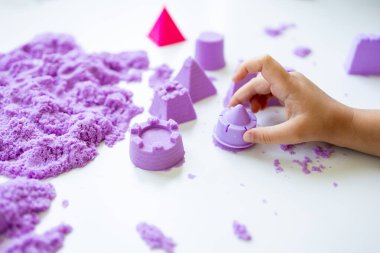 Çocuk eli mor kinetik kum ve kalıplarla oynuyor. Yüksek kalite.