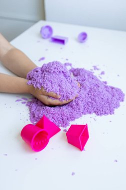 Çocuk elleri masada mor kinetik kumla ve şekilli şekillerle oynuyorlar. Yüksek kalite.