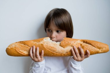 Beyaz arka planda büyük bir baget yiyen beyaz bir çocuk..