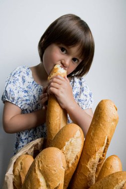 Beyaz arka planda taze Fransız ekmeğinin tadını çıkaran beyaz bir kız..