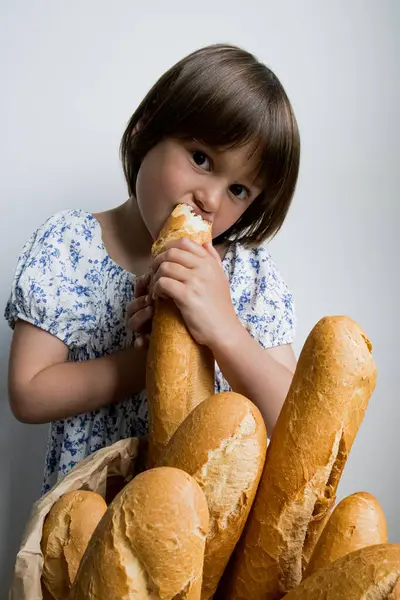 Beyaz arka planda taze Fransız ekmeğinin tadını çıkaran beyaz bir kız..