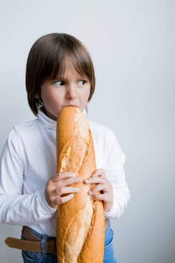 Beyaz arka plana karşı düşünceli bir ifadeyle baget yiyen beyaz bir çocuk..