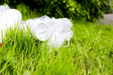 Plastik kaplar güneşli park ortamında yeşil çimenleri kirletiyor. Yüksek kalite.