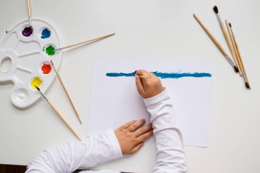 Fırça ve palet kullanarak maviye boyanmış çocuk resmi.