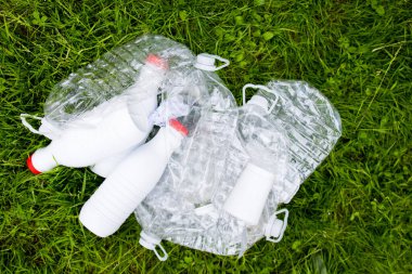 Yeşil çimenlerin üzerindeki plastik şişeler ve kaplar çevresel kaygıları vurguluyor. Yüksek kalite.
