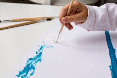 Beyaz tuval üzerinde fırçayla çocuk resmi.