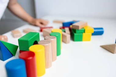 Arka planda çocuk eli olan beyaz masanın üzerinde renkli tahta bloklar. Yüksek kalite.
