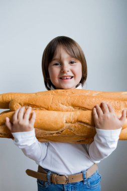 Beyaz arka planda büyük ekmekler tutan gülümseyen beyaz çocuk..