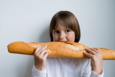 Genç beyaz çocuk elinde tuhaf bir ifadeyle büyük bir baget tutuyor..