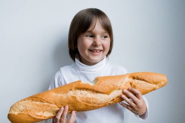 Beyaz arka planda baget tutan beyaz bir çocuk gülümsüyor..