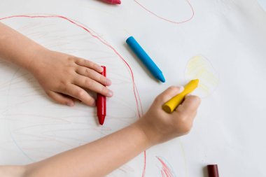 Beyaz kağıda renkli boya kalemleri çizen çocuk..