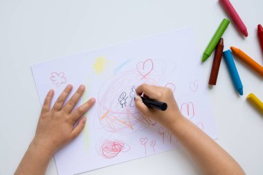 Beyaz kağıda renkli boya kalemleri çizen çocuk..