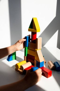 Güneş ışığında renkli tahta bloklarla oynayan bir çocuk. Yüksek kalite.