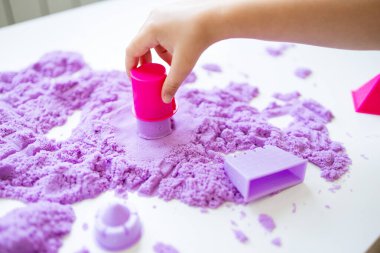 Mor kinetik kum ve oyuncaklarla heykel yapan çocuk eli. Yüksek kalite.