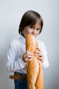 Genç beyaz çocuk içeride baget yemekten hoşlanıyor..