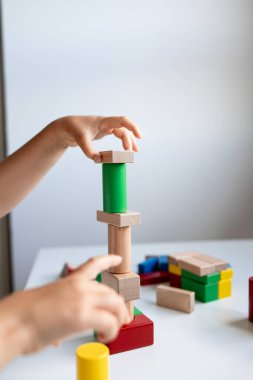 Beyaz masanın üzerinde renkli tahta bloklar olan çocuk inşa kulesi. Yüksek kalite.