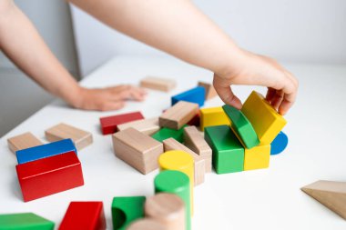 Beyaz bir masada renkli tahta bloklarla oynayan bir çocuk. Yüksek kalite.